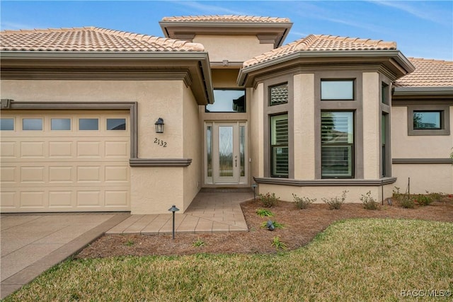 entrance to property featuring a garage and a lawn