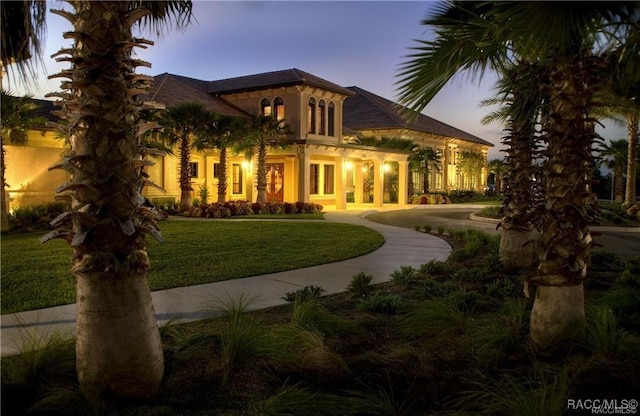 back house at dusk with a lawn