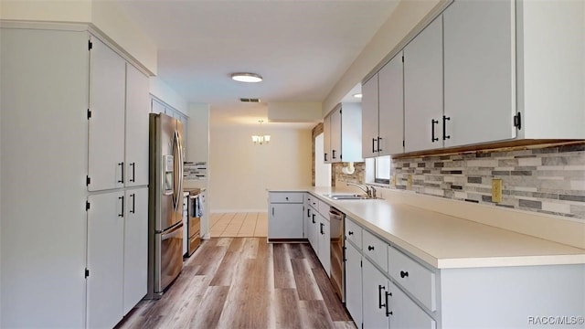 125 W Seymeria Dr, Beverly Hills, FL 34465 - kitchen featuring decorative backsplash, appliances with stainless steel finishes, light wood finished floors, light countertops, and a chandelier