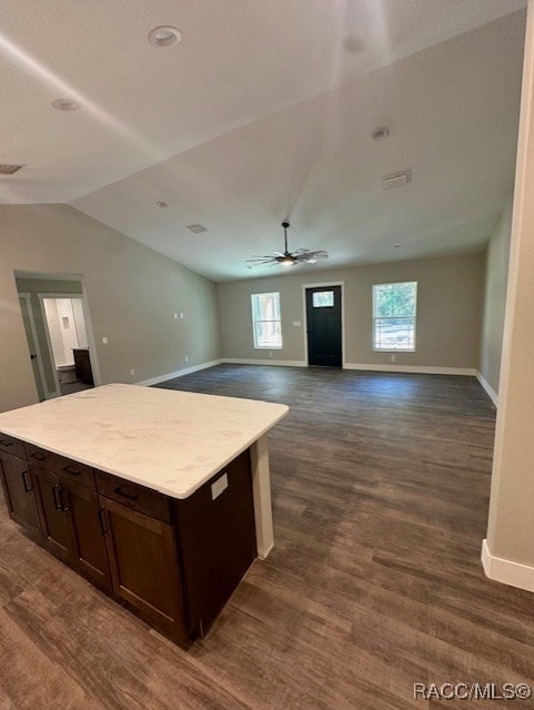 kitchen with lofted ceiling, dark wood-type flooring, ceiling fan, a kitchen island, and a healthy amount of sunlight