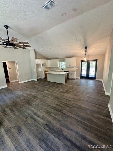 unfurnished living room with ceiling fan, dark hardwood / wood-style flooring, lofted ceiling, and french doors