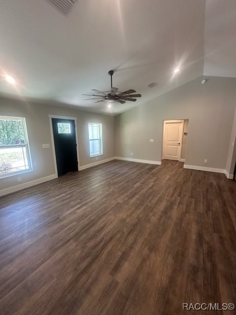 unfurnished living room with dark wood-type flooring, plenty of natural light, and a ceiling fan