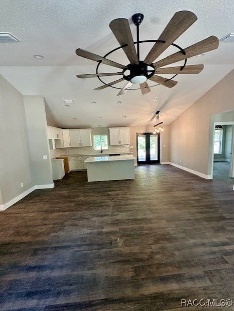 unfurnished living room featuring lofted ceiling, french doors, ceiling fan, dark hardwood / wood-style floors, and a textured ceiling