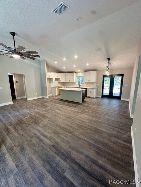 unfurnished living room featuring ceiling fan, dark hardwood / wood-style flooring, lofted ceiling, and french doors