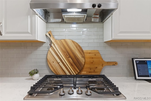 kitchen with white cabinets, tasteful backsplash, stainless steel gas stovetop, and wall chimney range hood