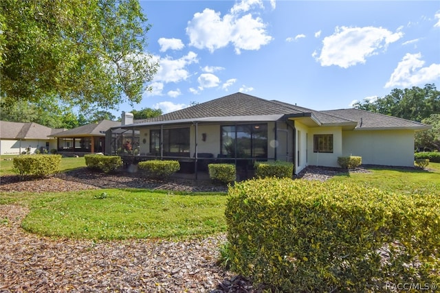 back of property with a yard and a sunroom