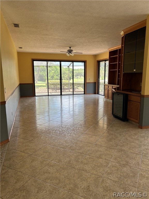 empty room with plenty of natural light, ceiling fan, and a textured ceiling