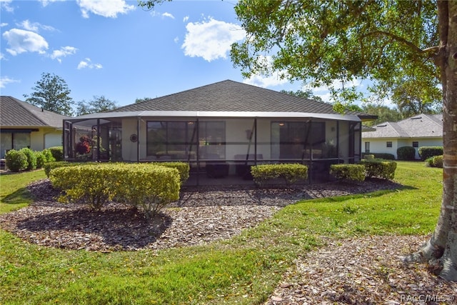 rear view of house featuring a lawn and a sunroom