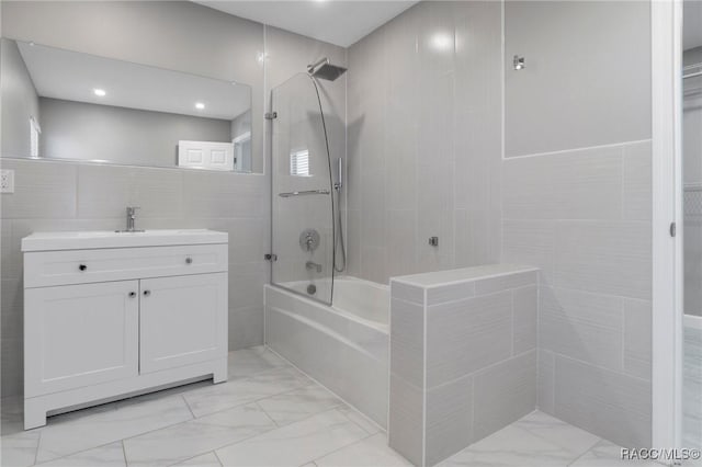 bathroom with vanity, tile walls, and tiled shower / bath