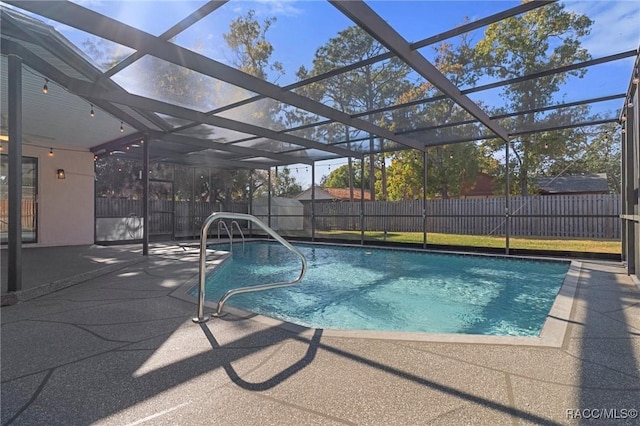 view of swimming pool with glass enclosure, a storage unit, and a patio area