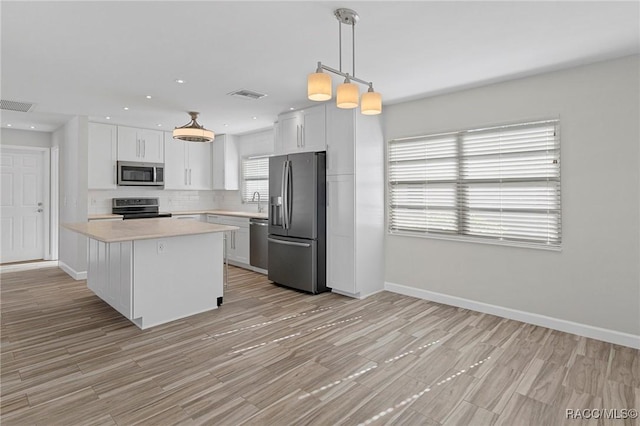 kitchen featuring a center island, white cabinets, hanging light fixtures, and appliances with stainless steel finishes