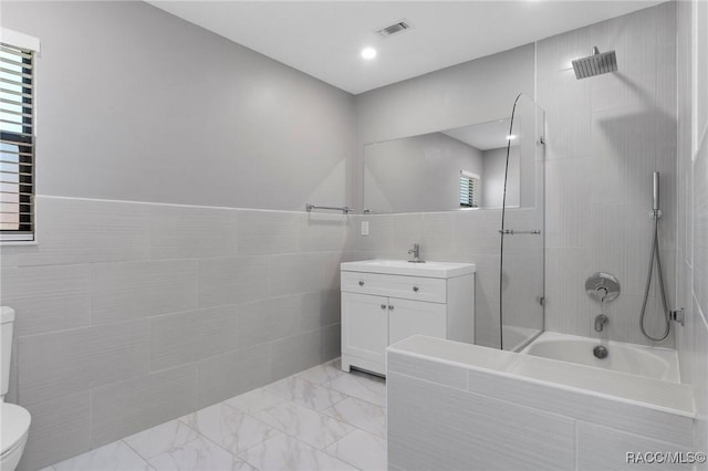 full bathroom with plenty of natural light, toilet, tile walls, and vanity