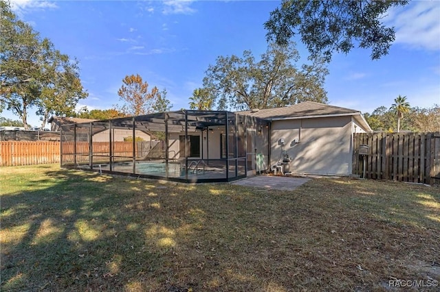 rear view of house with a lanai, a patio area, a lawn, and a fenced in pool