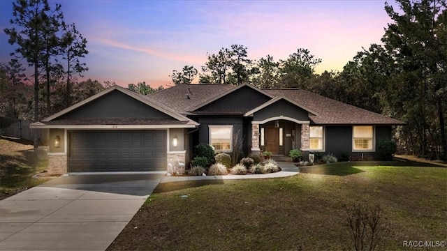 view of front facade featuring a garage, concrete driveway, a lawn, and stone siding