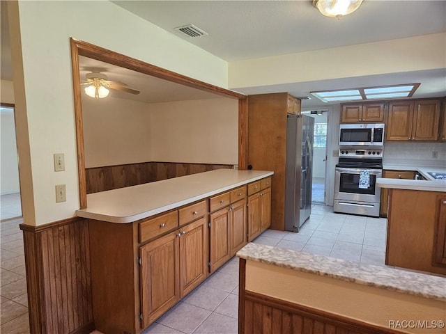 7781 N Lazy Trl, Crystal River, FL 34428 - kitchen featuring appliances with stainless steel finishes, light countertops, ceiling fan, a wainscoted wall, and light tile patterned floors