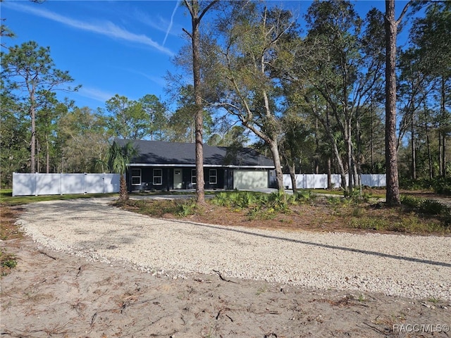 ranch-style home featuring fence and dirt driveway