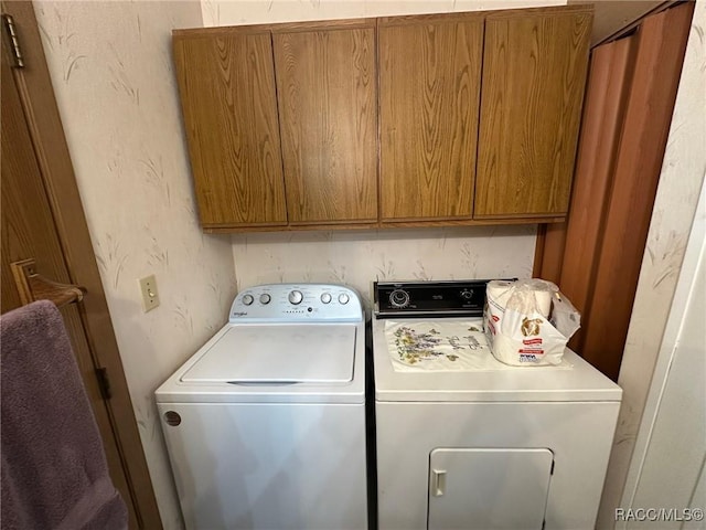 washroom with washing machine and clothes dryer and cabinet space