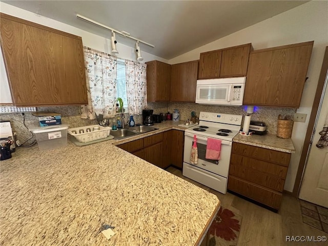 kitchen with a sink, white appliances, light countertops, and vaulted ceiling