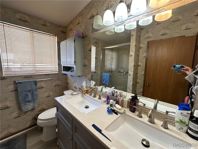 full bathroom featuring a sink, toilet, a stall shower, and wallpapered walls