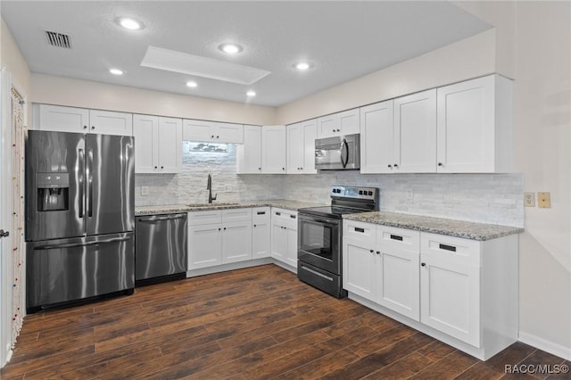 kitchen featuring sink, light stone counters, dark hardwood / wood-style floors, stainless steel appliances, and white cabinets