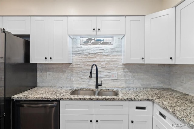 kitchen with sink, white cabinets, decorative backsplash, stainless steel dishwasher, and black fridge