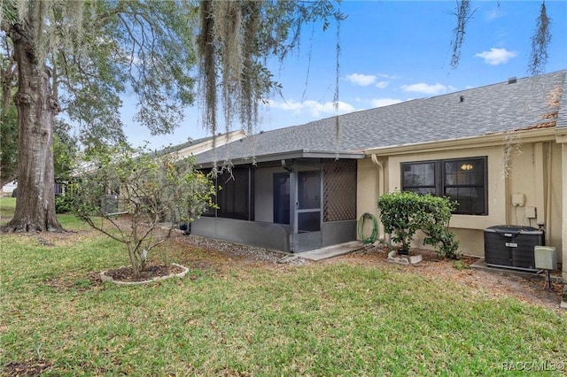 back of property with a sunroom, central AC, and a lawn