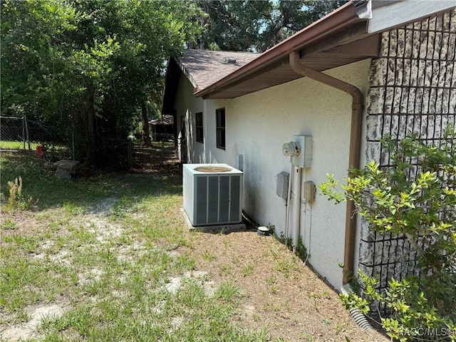 2098 W Deer Trail Ln, Lecanto, FL 34461 - view of side of property with stucco siding, central air condition unit, fence, and a shingled roof