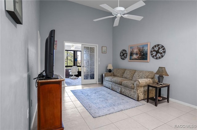 living room with ceiling fan, high vaulted ceiling, light tile patterned flooring, and baseboards