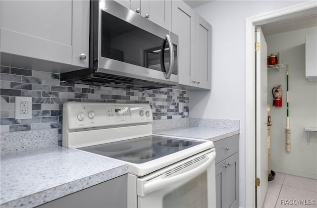 kitchen featuring stainless steel microwave, light countertops, white range with electric cooktop, and gray cabinets