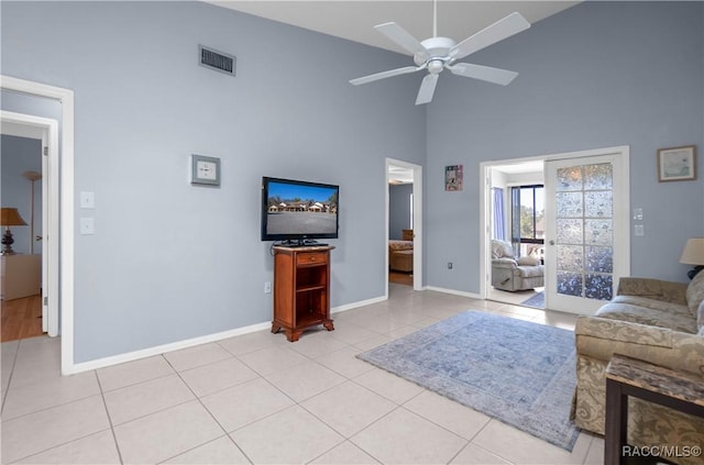 living area featuring high vaulted ceiling, light tile patterned flooring, visible vents, baseboards, and a ceiling fan