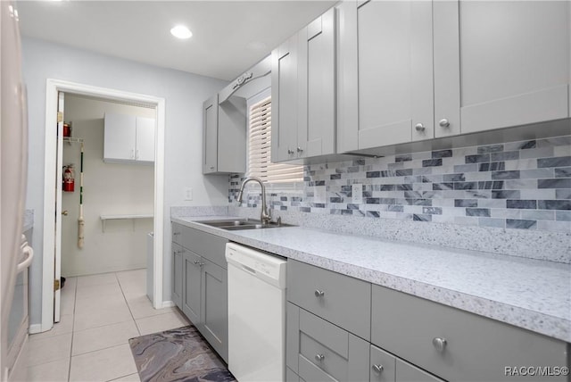 kitchen featuring light tile patterned floors, a sink, light countertops, dishwasher, and tasteful backsplash