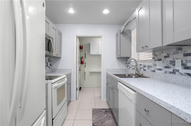 kitchen featuring light tile patterned floors, light countertops, backsplash, a sink, and white appliances