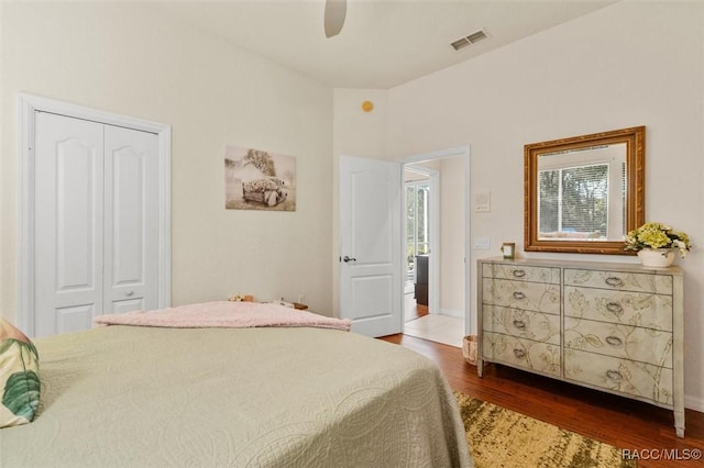 bedroom with ceiling fan, wood finished floors, visible vents, baseboards, and a closet