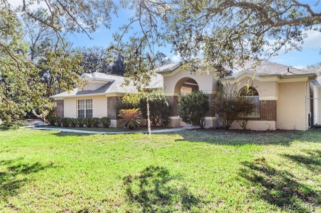 view of front of house featuring brick siding, a front lawn, and stucco siding