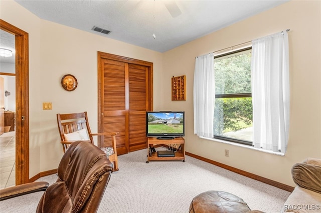 living area with ceiling fan and light colored carpet