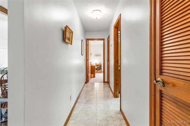 corridor with light tile patterned floors and a textured ceiling