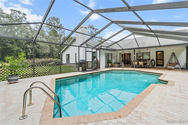 view of pool featuring glass enclosure, ceiling fan, and a patio area