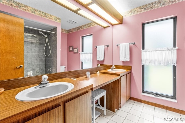 bathroom with tile patterned flooring, a tile shower, vanity, and toilet