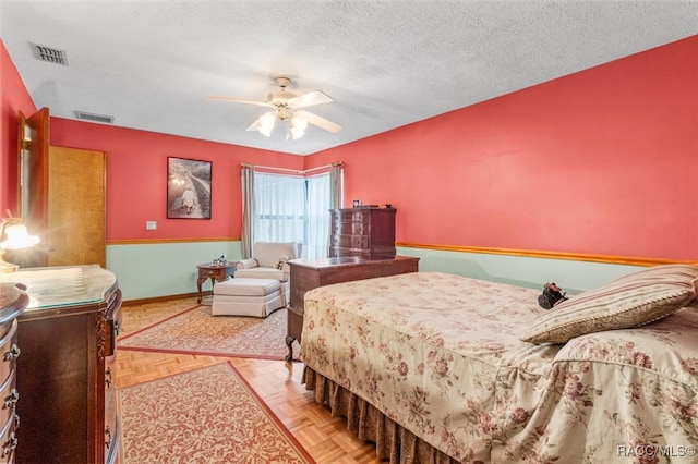 bedroom with a textured ceiling, light parquet floors, and ceiling fan