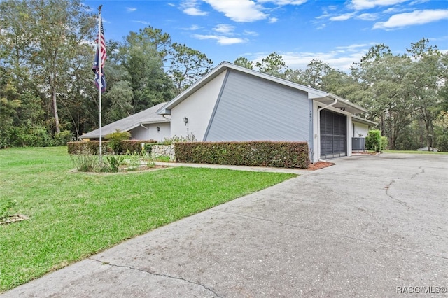 view of side of property featuring central air condition unit, a garage, and a lawn