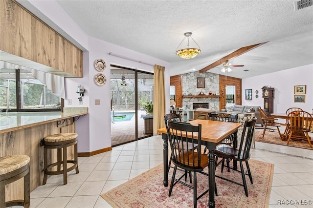 dining room with a fireplace, light tile patterned floors, a textured ceiling, and ceiling fan