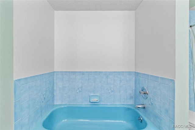 bathroom featuring a washtub and a textured ceiling