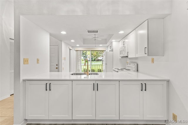 kitchen with light stone counters, white appliances, ceiling fan, sink, and white cabinetry