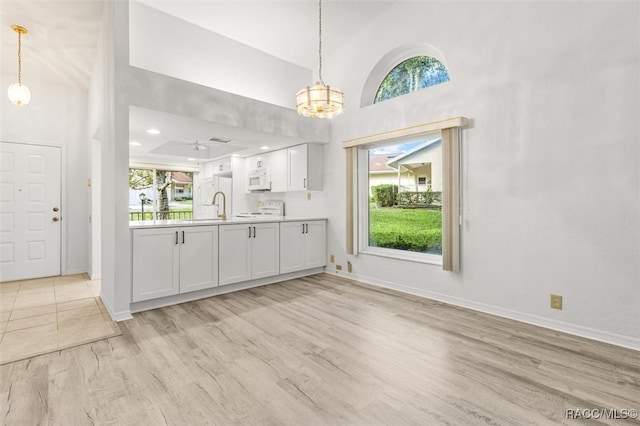 kitchen with white cabinetry, high vaulted ceiling, white appliances, and light wood-type flooring