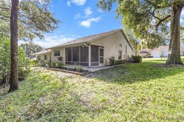 back of house featuring a lawn and a sunroom