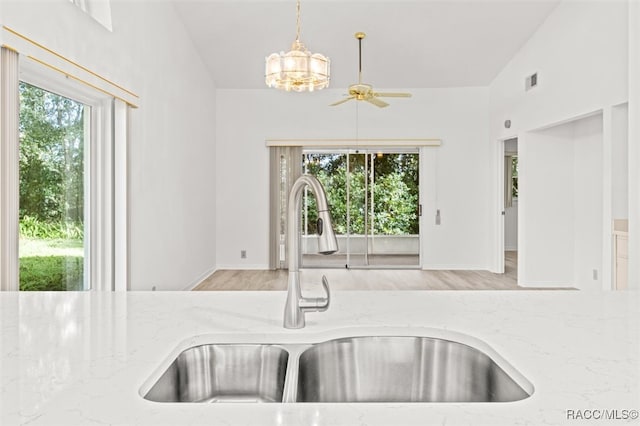 kitchen with light stone countertops, plenty of natural light, vaulted ceiling, and sink