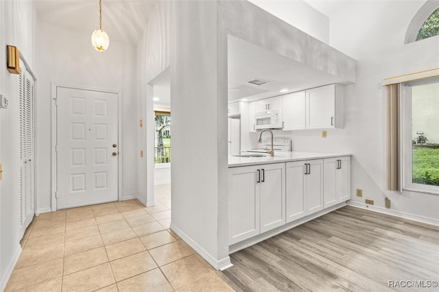 kitchen featuring light wood-type flooring, white cabinetry, a wealth of natural light, and sink