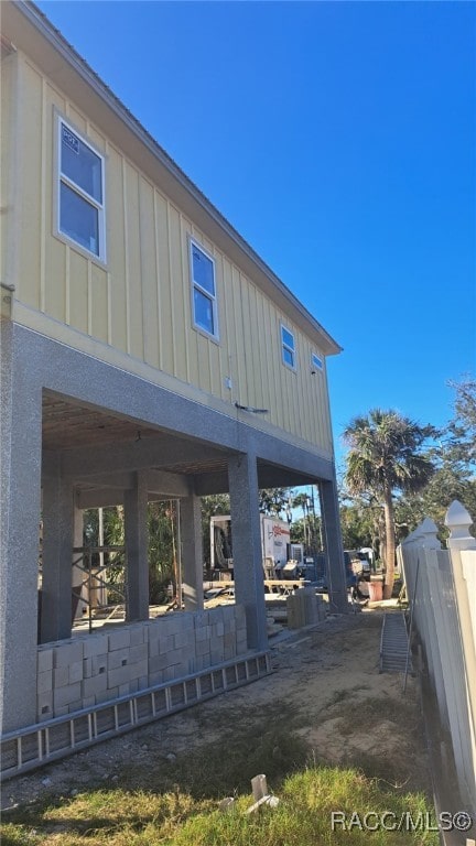 rear view of house with board and batten siding, a patio, and fence