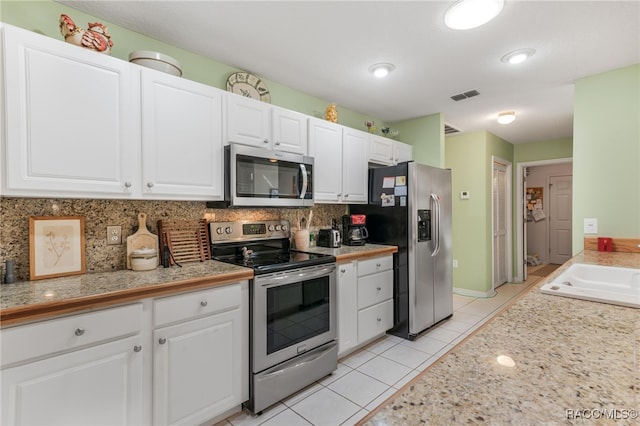 kitchen featuring white cabinetry, appliances with stainless steel finishes, light tile patterned flooring, and tasteful backsplash