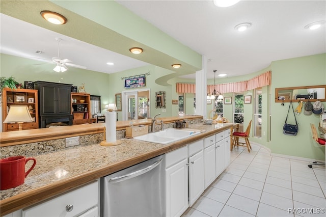 kitchen featuring pendant lighting, white cabinetry, sink, stainless steel dishwasher, and light tile patterned floors